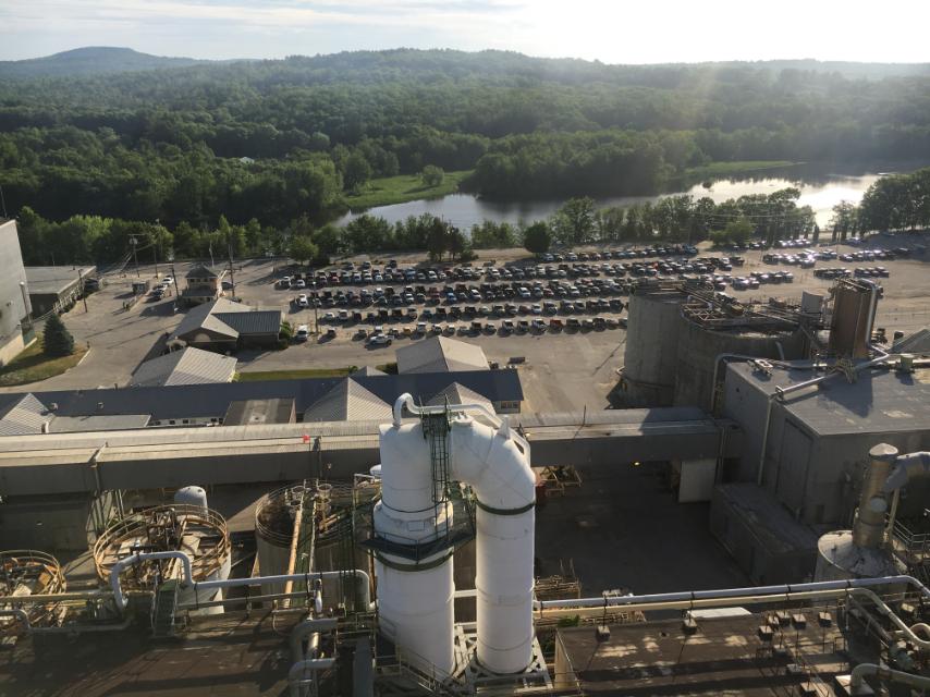 Aerial view of an industrial pulp and paper facility with surrounding forest and lake